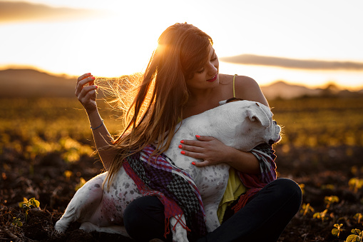 A beautiful woman playing with her dog at sunset