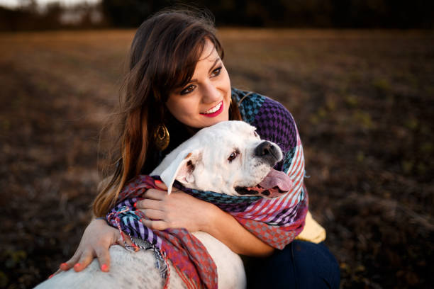 A beautiful woman playing with her white boxer dog