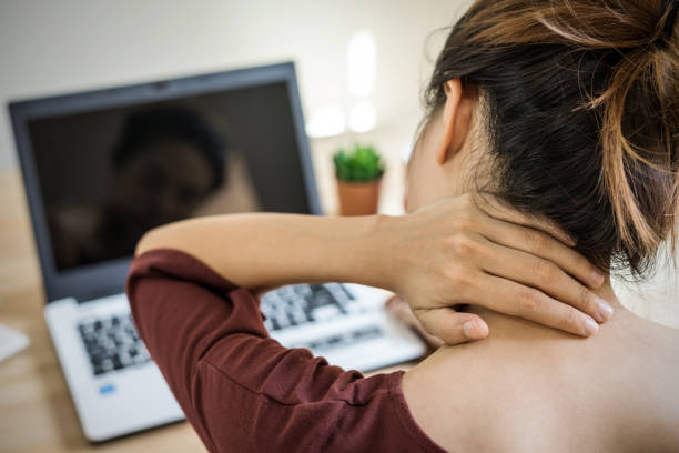 Young woman working at home and having neck pain stock photo