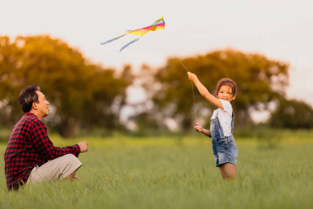 asiatiska barn flicka och far med en drake kör och glad på ängen på sommaren i naturen - flying kite bildbanksfoton och bilder