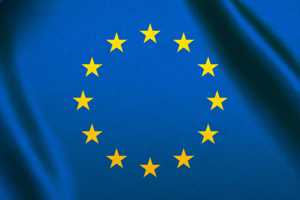 EU flag. European Union flag on a flagpole waving on a bright blue sky background