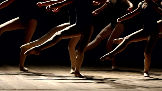 A group of ballerinas dancing on stage in the dark