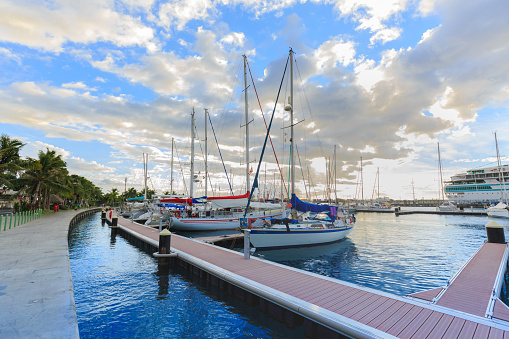 Papeete, French Polynesia – March 10, 2018 :  The sailing boat park in sunset time at Large seaport in Tahiti PAPEETE, FRENCH POLYNESIA.