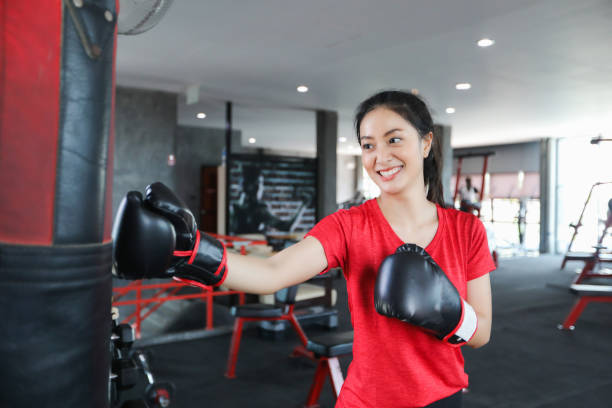 Beautiful women asian boxer happy and fun fitness boxing and Punching A Bag With wearing boxing gloves. stock photo