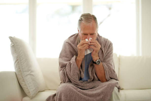 Laid up with the flu Shot of a senior man blowing his nose with a tissue at home cold virus stock pictures, royalty-free photos & images