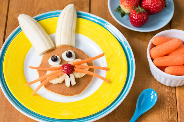 Funny healthy breakfast for kids on Easter. Easter bunny pancake on yellow plate Funny healthy breakfast for kids on Easter. Easter bunny pancake on yellow plate. Closeup view, selective focus bunny pancake stock pictures, royalty-free photos & images