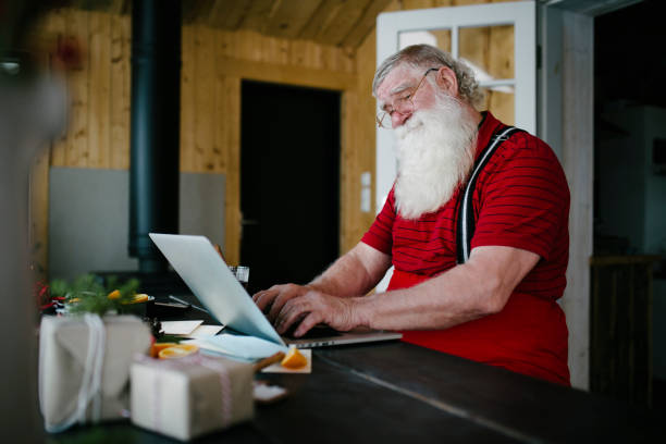 Santa Claus in his living room using laptop