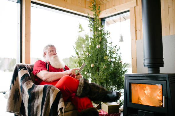 istock Santa Claus using digital tablet in front of a fireplace 931126020