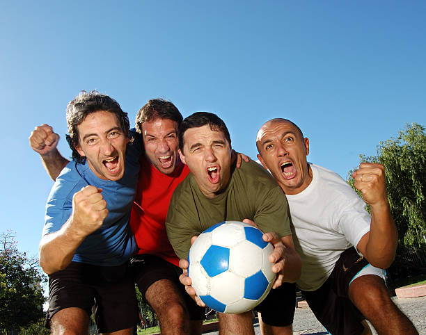 istock A man holds a soccer ball while 3 others hold up their fists 93112662