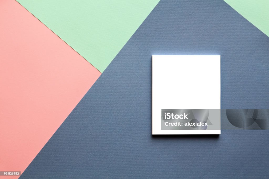 Abstract geometric watercolor paper background in trend colors with notebook. Abstract geometric watercolor paper background in soft pastel pink and blue trend colors with white notebook on it. Paper Stock Photo