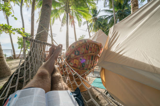 Point of view of man relaxing in hammock in camping Personal perspective of young man lying on sofa in front of luxury tent in clamping campsite under the coconut palm trees in the Islands of the Philippines tropical climate people relaxation vacations concept. siquijor island stock pictures, royalty-free photos & images