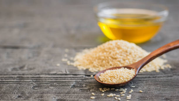 istock Sesame seeds, oil cup and spoon on dark wooden table. 931131190