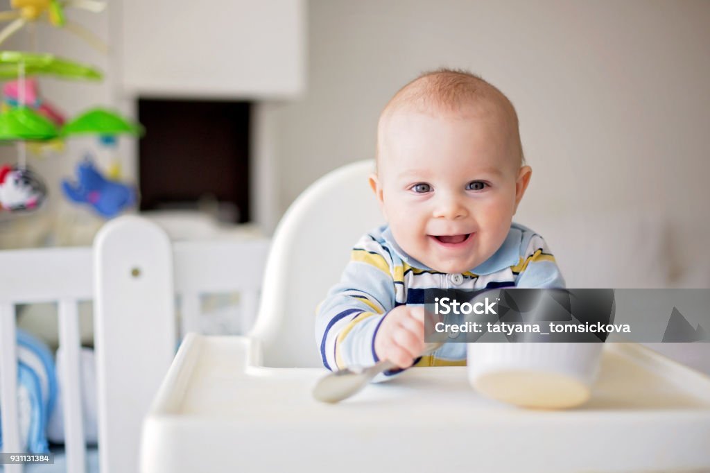 Cute little baby boy, eating mashed vegetables for lunch, mom feeding him Cute little baby boy, eating mashed vegetables for lunch, mom feeding him, sweet toddler boy, smiling Baby - Human Age Stock Photo