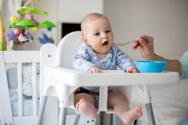 istock Cute little baby boy, eating mashed vegetables for lunch, mom feeding him 931131552