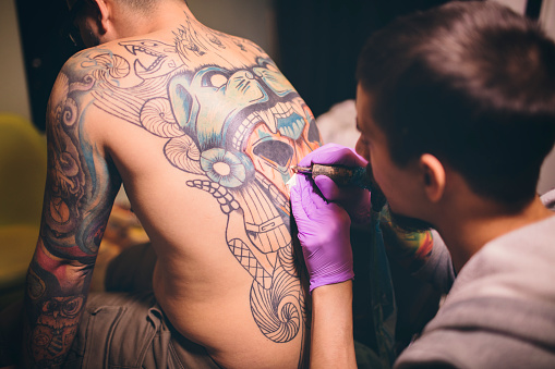 Tattoo artist tattooing his client in his workshop.