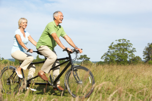 Mature couple riding tandem in field