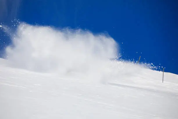 Photo of Skiing and snowboarding background. Snow splash. Skier turning on a blue sky day  Ski slope.  Beautiful winter nature. Fresh snow on the top of  mountains.  High mountain landscape  Ski area.