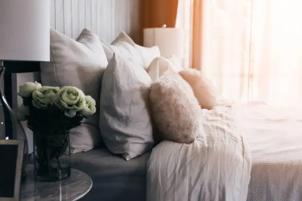 Photo of light soft pillow on beautiful bed cozy bedroom with sun light from window interior concept