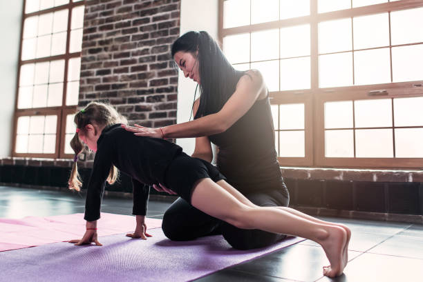 junge trainer helfen kleine mädchen plank trainieren im sportverein - yoga good posture women little girls stock-fotos und bilder