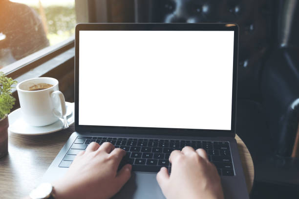 istock Mockup image of hands using and typing on laptop with blank white desktop screen and coffee cup 931159104