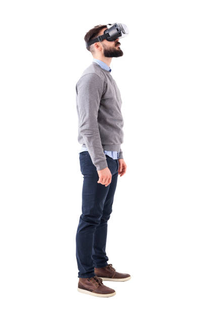 Side view of speechless young man having virtual reality glasses experience looking up above stock photo