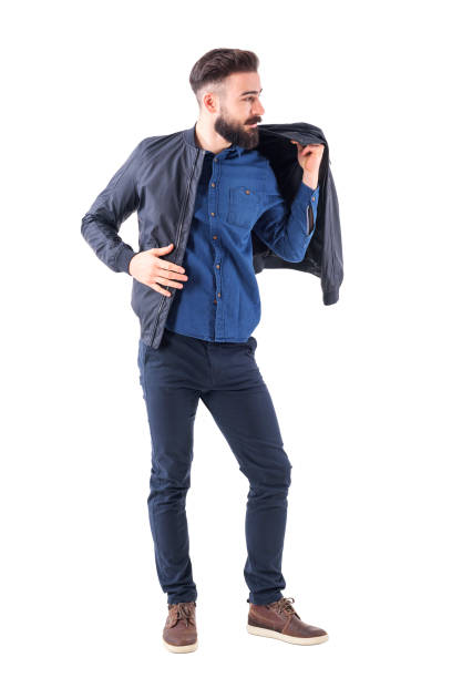 Bearded handsome man putting on bomber jacket and looking away