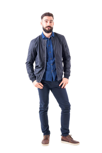 istock Young man in blue shirt and bomber jacket with thumbs in pockets looking at camera 931173756