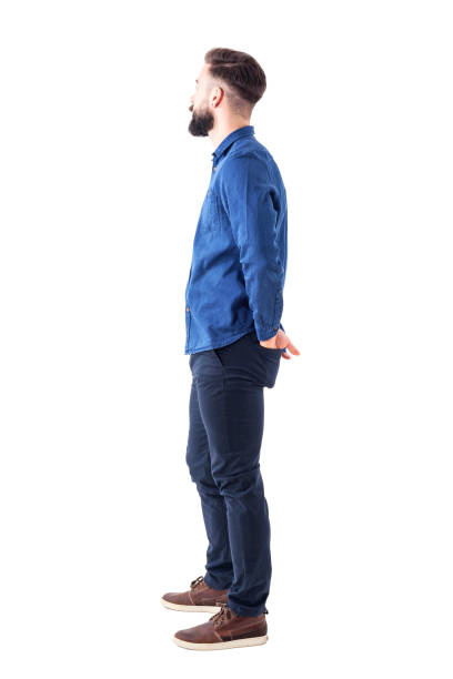 Side view of young stylish bearded man with hands in back pockets standing and watching Side view of young stylish bearded man with hands in back pockets standing and watching. Full body isolated on white background. full body isolated stock pictures, royalty-free photos & images