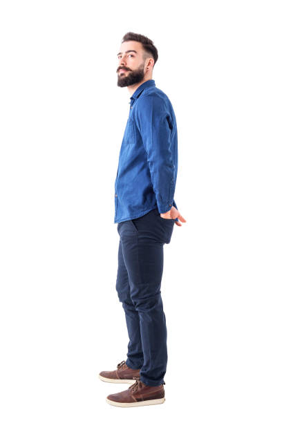 istock Young stylish bearded smart casual man watching above with hands in back pockets. 931178710