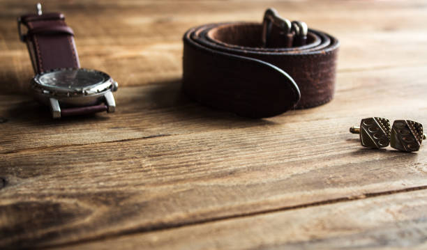 watches and belt and cufflincs on wooden background