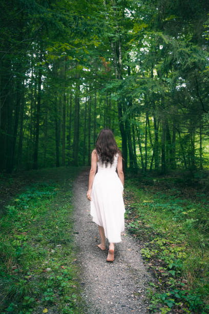 istock Woman in a white dress walking through a forest 931182936