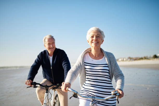 bonheur est votre vélo sur la plage - senior couple cycling beach bicycle photos et images de collection