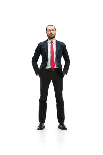 Full body or full-length portrait of businessman on white studio background. Serious bearded young man in glasses, suit, red tie standing in office. Business, career, success concept.