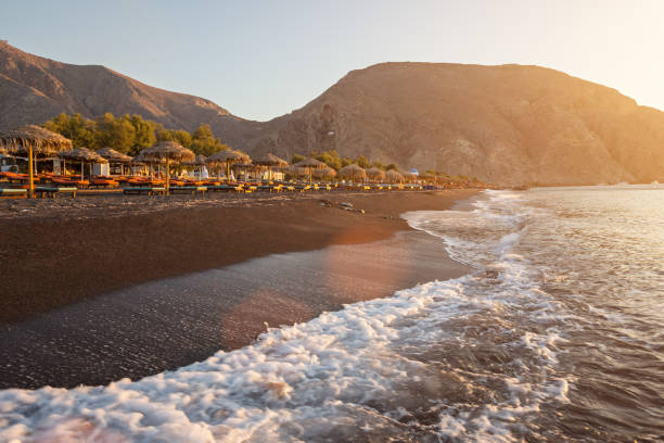 perissa strand bei sonnenaufgang auf der griechischen insel santorini - black sand beach santorini greece stock-fotos und bilder