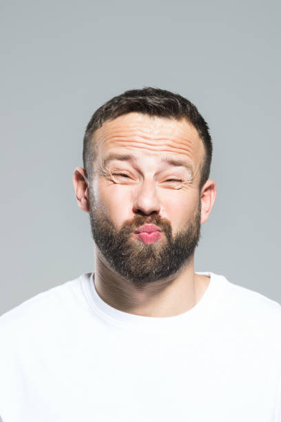 istock Headshot of bearded young man making funny face, grey background 931197614