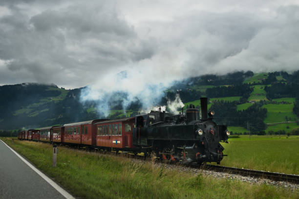 istock Retro locomotive with smoking engine moving forward in Alps mountains 931197760