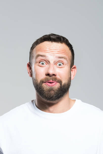 Headshot of surprised bearded young man, grey background