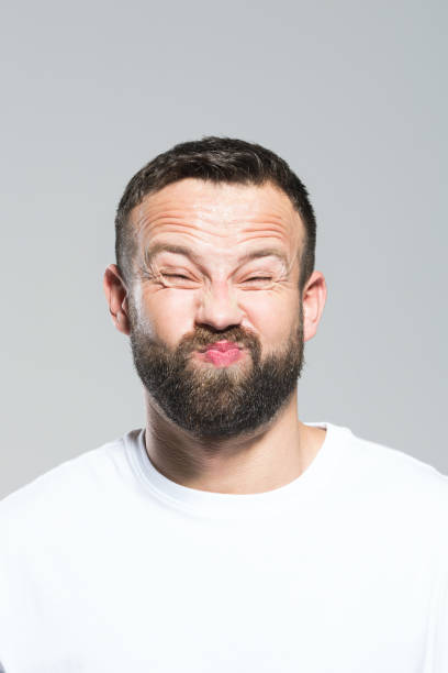 istock Headshot of bearded young man making funny face, grey background 931198664