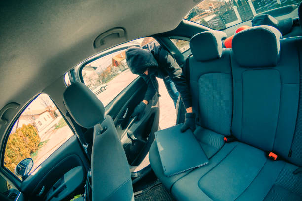 Thief breaking into car with screwdriver in broad daylight