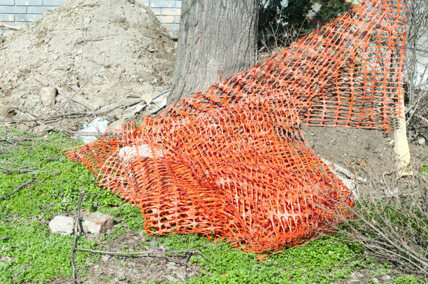istock Orange plastic safety net or barrier on the street to protect excavating construction site 931212404
