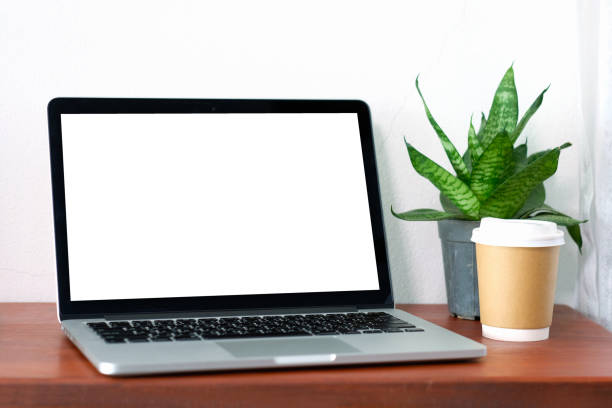 istock Laptop computer with blank screen and coffee cup on wood table background, mock up display, business and technology, online education, technology lifestyle concept 931212636