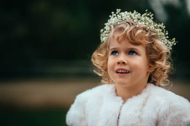 Portrait of beautiful smiling flower girl at wedding ceremony Portrait of beautiful little bridesmaid with floral crown and curly blond hair at wedding ceremony flower girl stock pictures, royalty-free photos & images