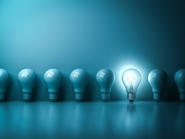 istock One glowing idea light bulb standing out from unlit incandescent bulbs on dark green pastel color background with reflection 931227338