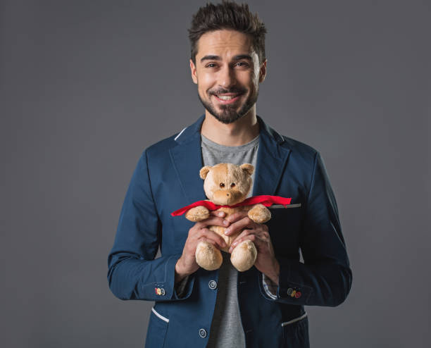 Cheerful smiling man standing with teddy bear Waist up portrait of happy joyful male holding in hands toy. Isolated on gray background man with teddy bear stock pictures, royalty-free photos & images