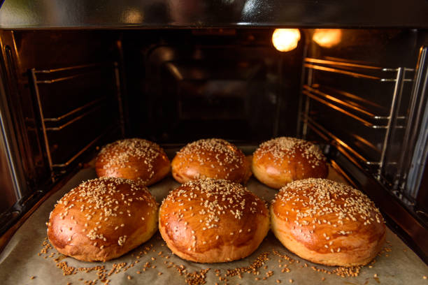 hamburguesa casera rollos espolvoreado con sésamo las semillas se cuecen al horno en el horno - freshness hamburger burger bread fotografías e imágenes de stock