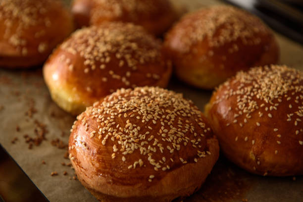 homemade burger rolls sprinkled with sesame seeds are baked in the oven homemade burger rolls sprinkled with sesame seeds are baked in the oven bun bread stock pictures, royalty-free photos & images