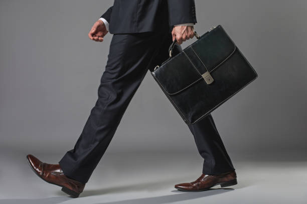 Young businessman going with a briefcase Low angle close up of male legs. Man walking in business suit with suitcase brown leg stock pictures, royalty-free photos & images