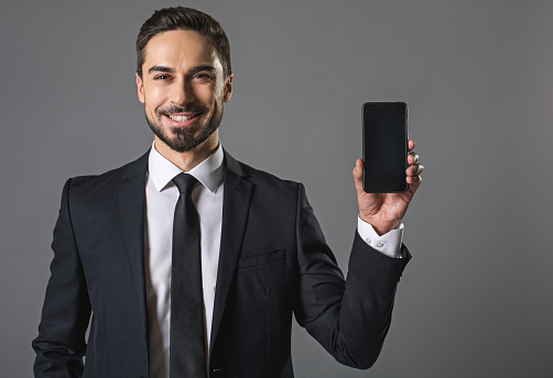 Waist up portrait of happy young cheerful man. He keep in hand new cellphone. Technology concept. Isolated on background and copy space right place