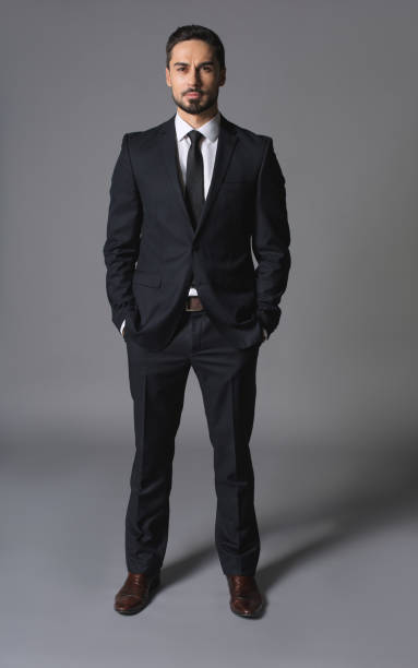 istock Young serious successful businessman standing with hands in pockets 931240432