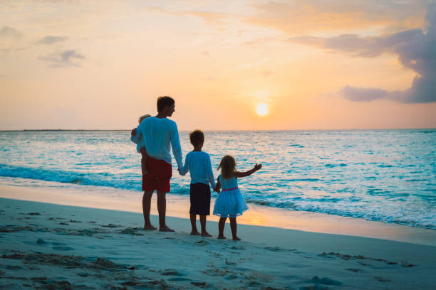 istock father and kids walking on beach at sunset 931243540